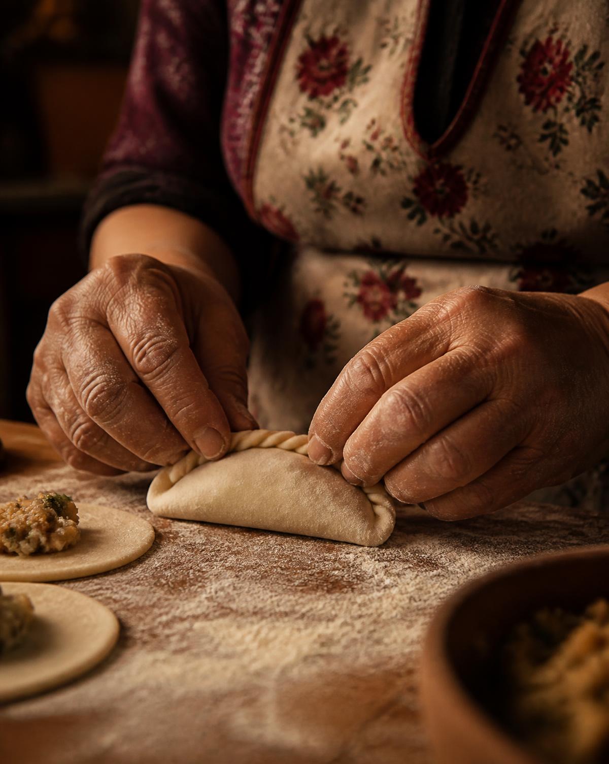 Hands crimping empanadilla dough on a floured board